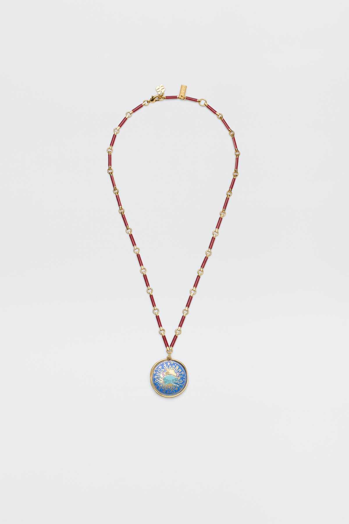 The Ari - Astro Cancer necklace features gold statement disc charms with alternating red and gold links and a round blue-and-gold sunburst pendant. Ideal as a zodiac necklace, it's shown on a plain white background.