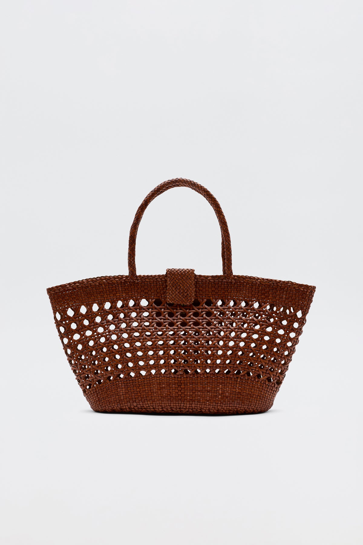 The Lucine - Tan is a brown woven straw tote bag with an openwork pattern, two handles, and a small flap closure, shown against a plain white background.