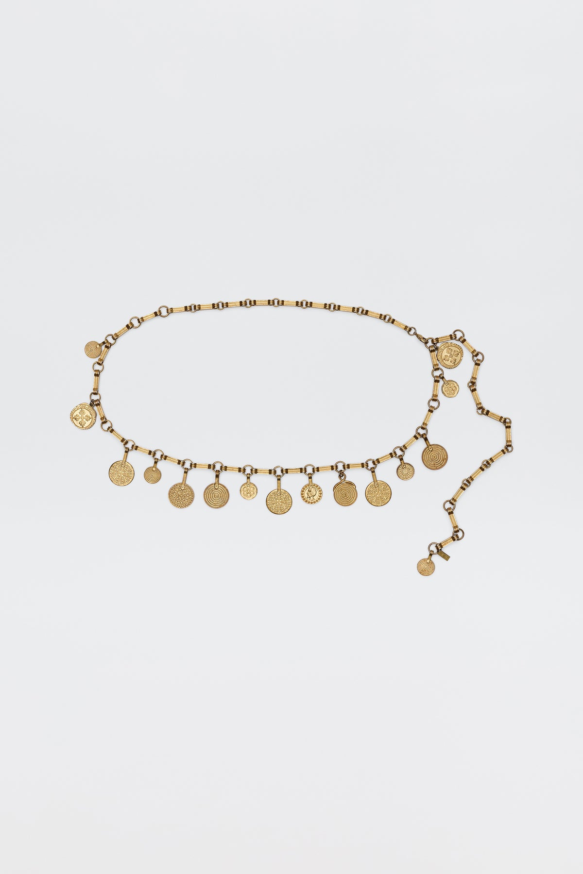 The Isolde - Gold belt features evenly spaced coin-shaped charms on a linked chain, bringing vintage glamour—ideal for pairing with RIXO dresses. Shown on a simple white background.