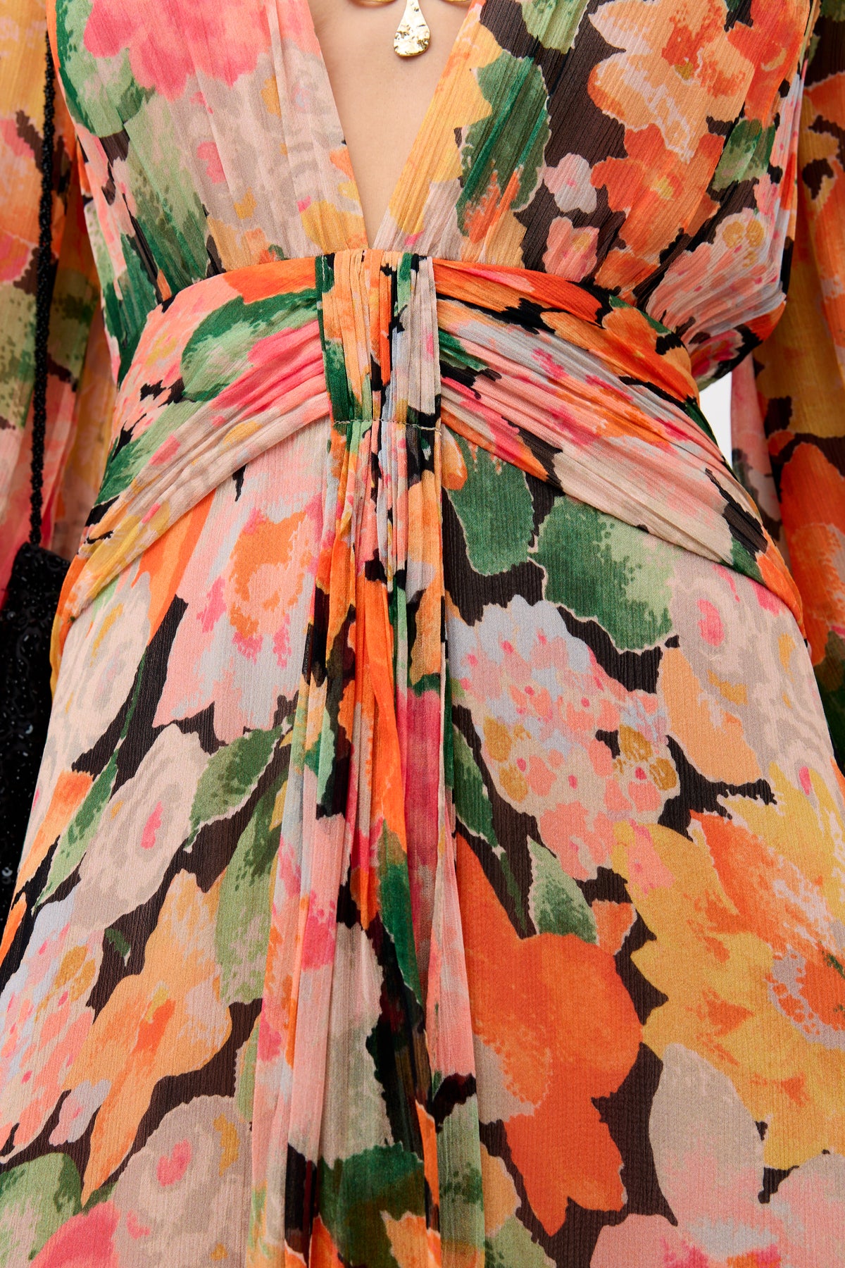 Close-up of the Meera - Chelsea Floral Black dress, featuring vibrant orange, yellow, pink, and green floral patterns, a deep V-neckline, and a gathered waist with a center knot detail.