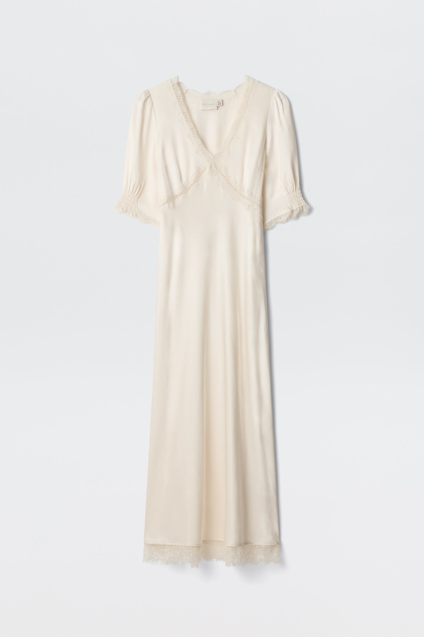 The Annina - Pearl is a cream satin dress with short puff sleeves, lace-trimmed neckline, sleeves, and hem, plus a subtle v-neckline. This vintage-inspired piece exudes elegant charm.