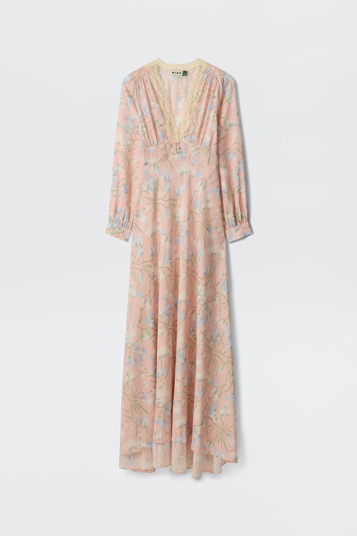 The Emory - Watercolour Floral Pink is a long, light pink dress featuring blue and green floral patterns, long sleeves, a lace-trimmed V-neckline, and an airy, flowing silhouette.