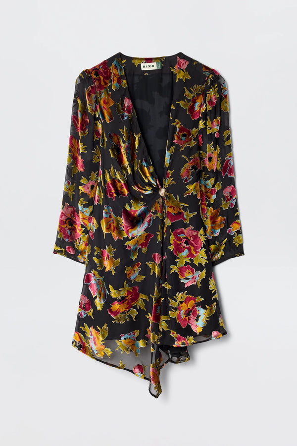 The Kensley - Countryside Devoré Black is a black cocktail dress with a vibrant red, yellow, and pink Devoré floral print, featuring a deep V-neckline and an asymmetrical draped hemline.