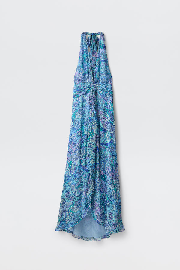 The Alaina - Paisley Floral Blue is a long, sleeveless halter dress with a flowing silhouette and blue and purple paisley floral pattern, shown on a plain white background.