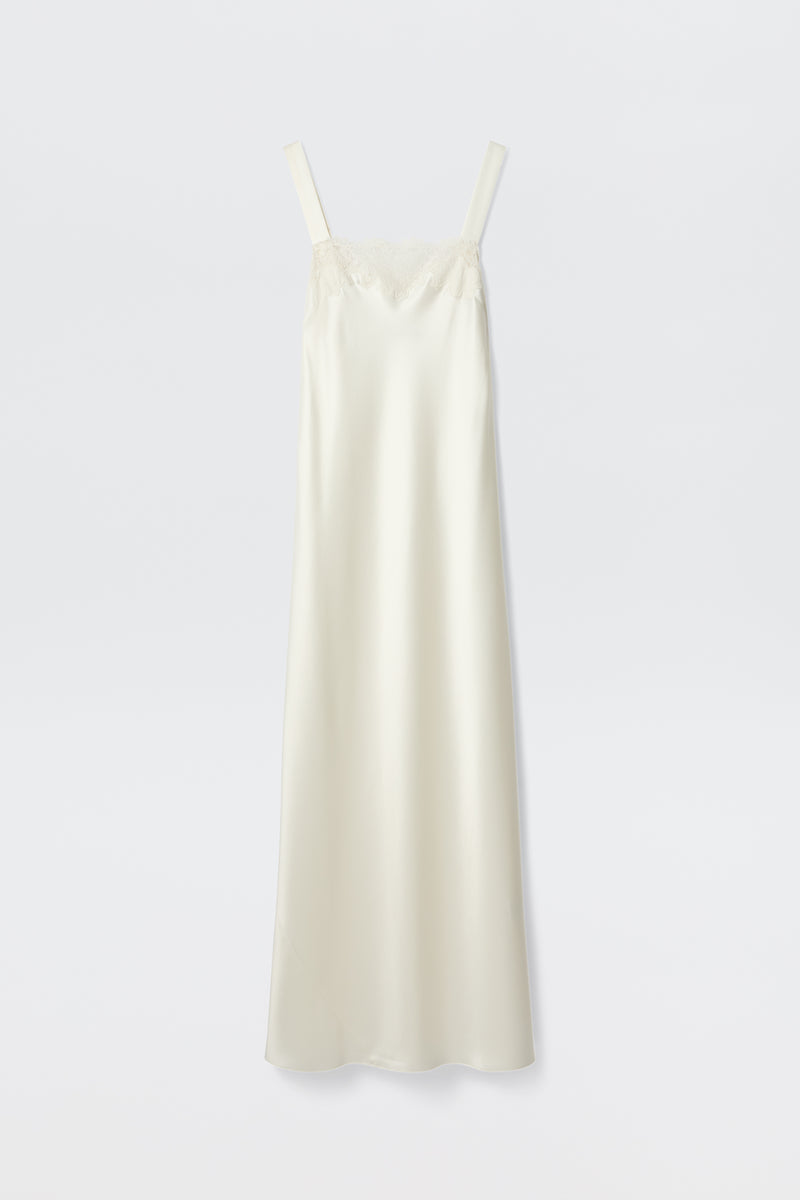 The Maybelle - Ivory is a long, cream-colored satin slip dress with wide shoulder straps and delicate lace trim on the straight neckline, shown against a plain white background.