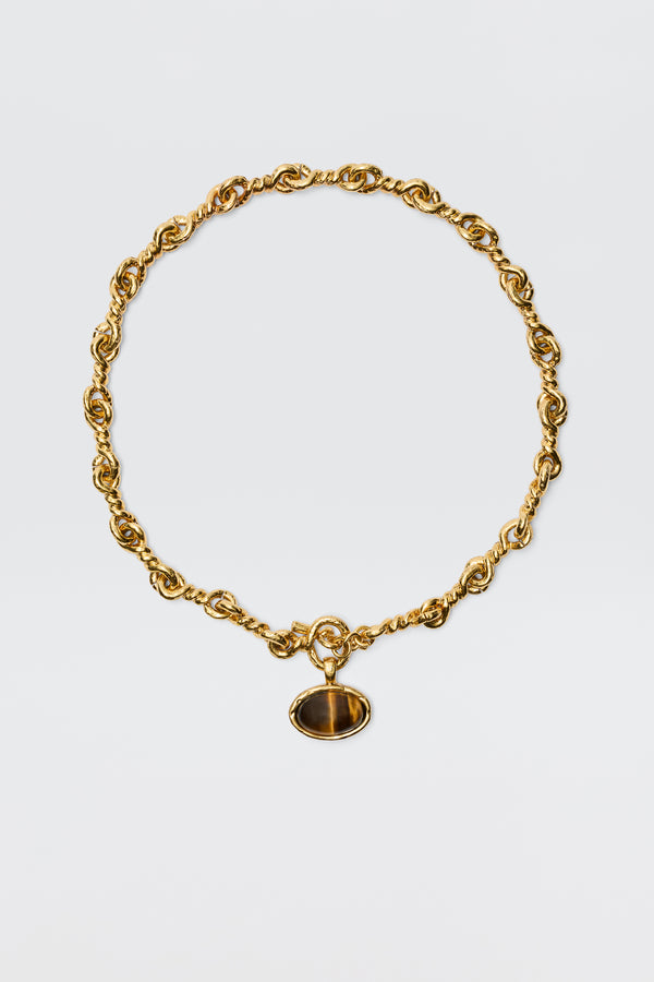 The Zandra - Gold features a chunky, vintage-inspired gold-plated chain with twisted links and an oval dark brown gemstone pendant set in a gold frame, shown against a plain white background.