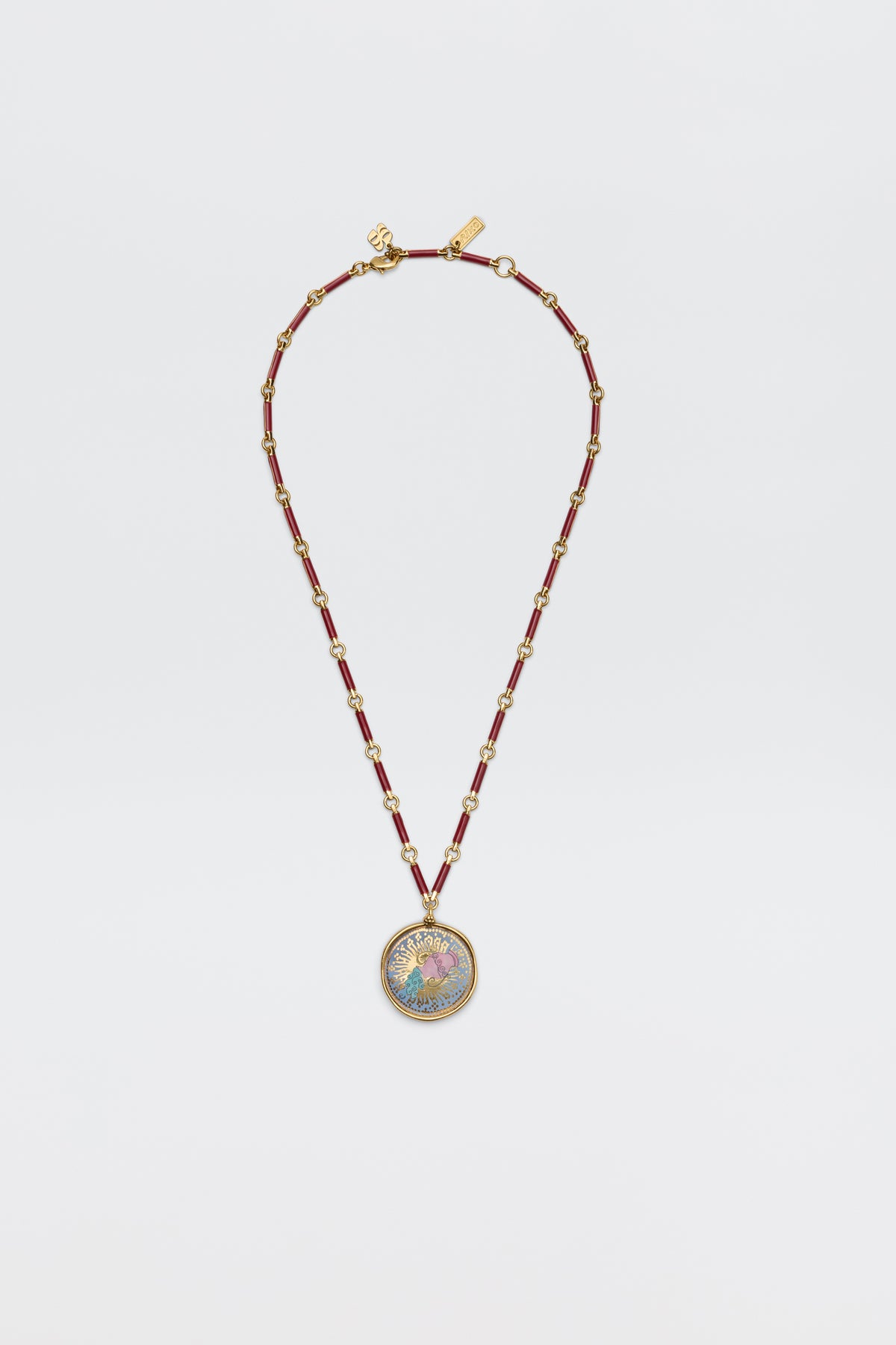 The Ari - Astro Aquarius necklace features gold zodiac detailing, red cylindrical beads, small gold spacers, and a statement disc charm with a colorful, intricate design at the center. Displayed against a plain white background.