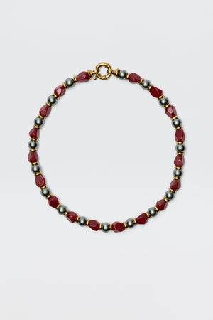 The Palmara - Burgundy necklace features alternating red geometric beads and round metallic silver beads with a gold clasp, showcased on a plain white background.