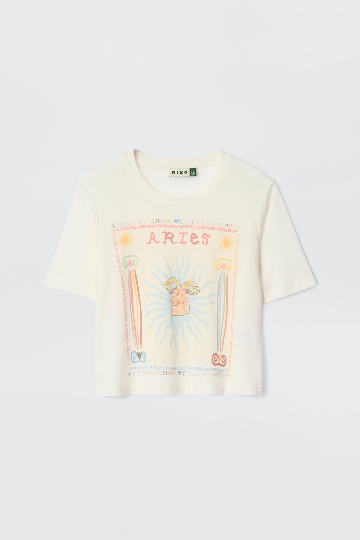 The Ria - Aries white short-sleeve T-shirt displays a vibrant Aries graphic with "ARIES" at the top, a central ram, sun rays, and pink, orange, and blue astrological symbols.