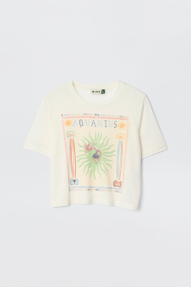 The Ria - Aquarius is a white short-sleeve tee with a vibrant Aquarius illustration, symbols, and a sunburst design—styled on a plain light background and perfect to pair with RIXO skirts for a chic look.