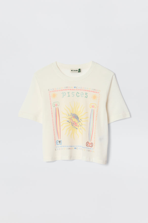 The Ria - Pisces is a white cropped hem T-shirt with a vibrant Pisces illustration—sun and fish at the center, surrounded by pastel astrological symbols and text. Pairs perfectly with RIXO skirts. Displayed against a plain background.