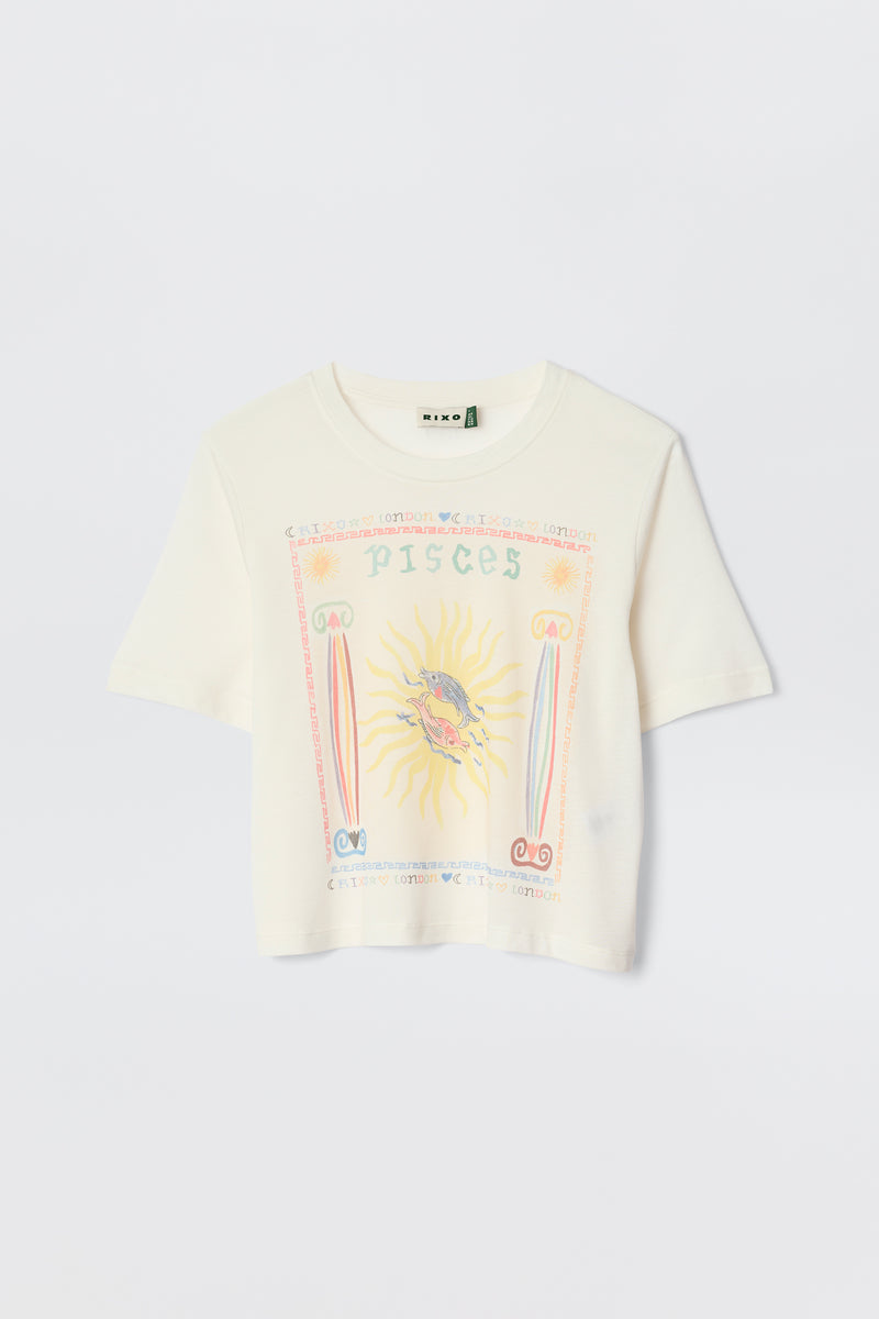 The Ria - Pisces is a white cropped hem T-shirt with a vibrant Pisces illustration—sun and fish at the center, surrounded by pastel astrological symbols and text. Pairs perfectly with RIXO skirts. Displayed against a plain background.