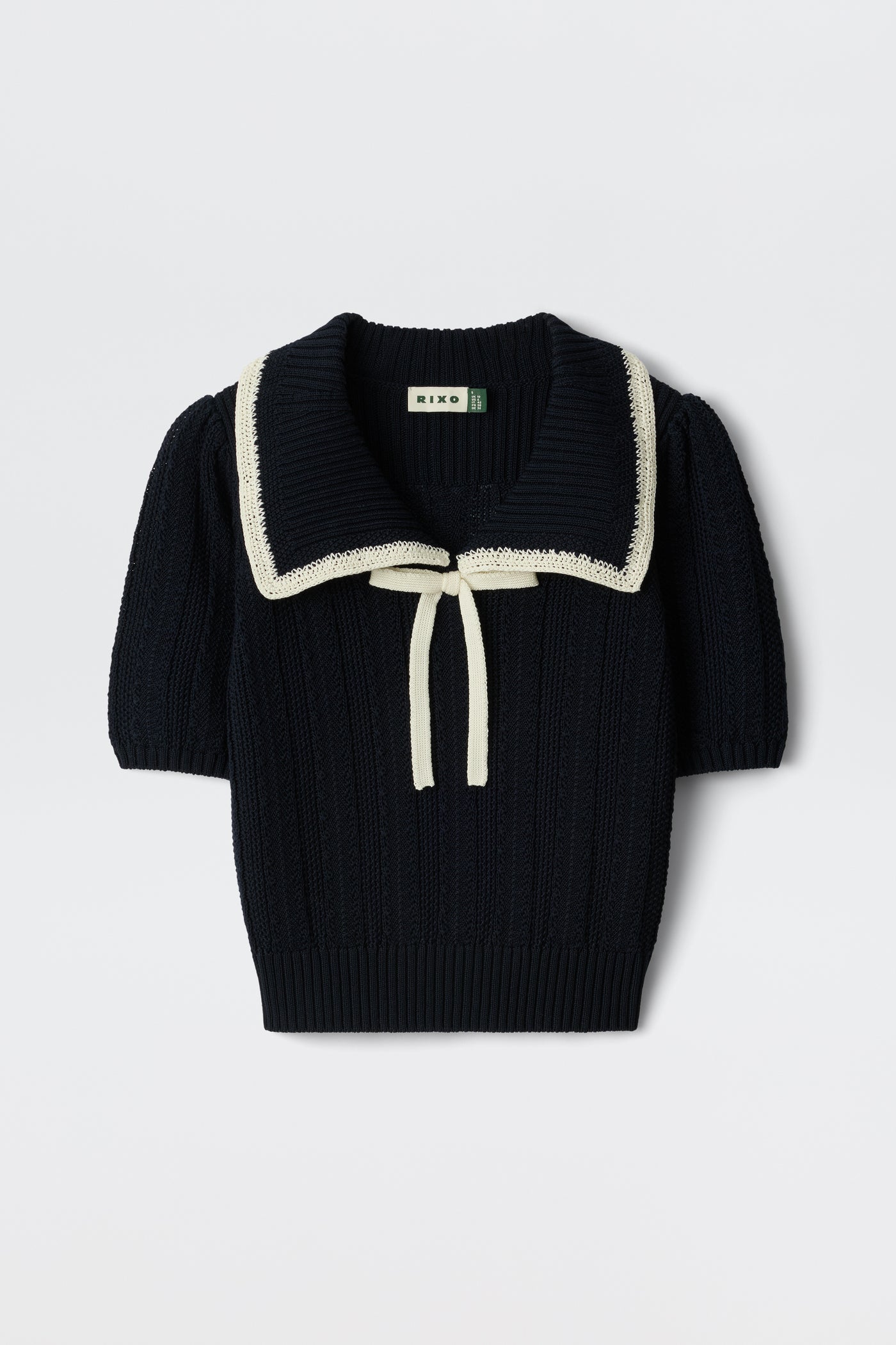 The Pippa - Deep Navy is a short-sleeved knit sweater featuring a wide white-trimmed sailor collar, cream front tie, ribbed texture, and a slightly cropped fit.