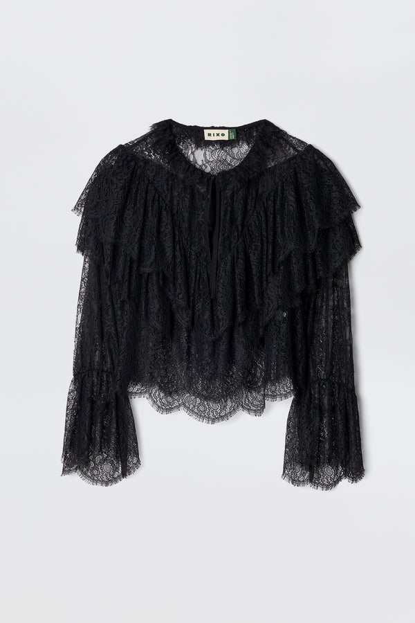 The Faryn - Black is a long-sleeve lace blouse featuring layered ruffles on the chest and sleeves with scalloped hem and cuffs, shown on a plain white background.