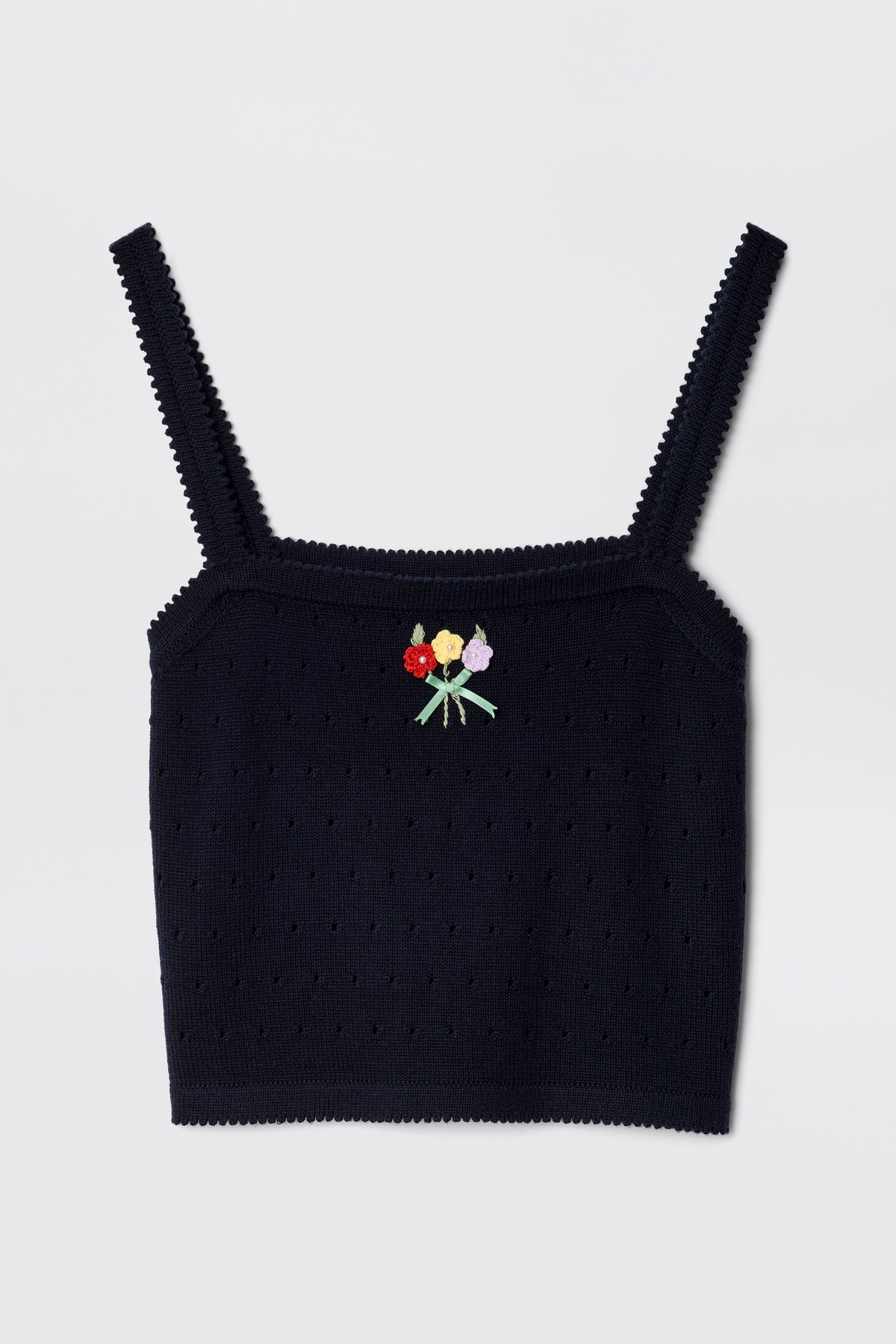 The Perla - Floret Embroidery Deep Navy is a black merino wool crop top with spaghetti straps, featuring a small embroidered bouquet of red, yellow, and pink flowers with green stems at the front center.