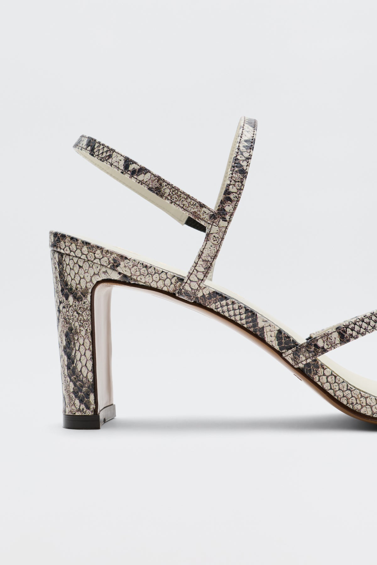 Introducing the Ciervo - Snakeskin: a high-heeled strappy leather sandal with an eye-catching snakeskin print, designed with two delicate straps over the foot and ankle and finished with a modern square heel. Photographed on a plain white background, it’s the ultimate complement to any RIXO occasion wear look.