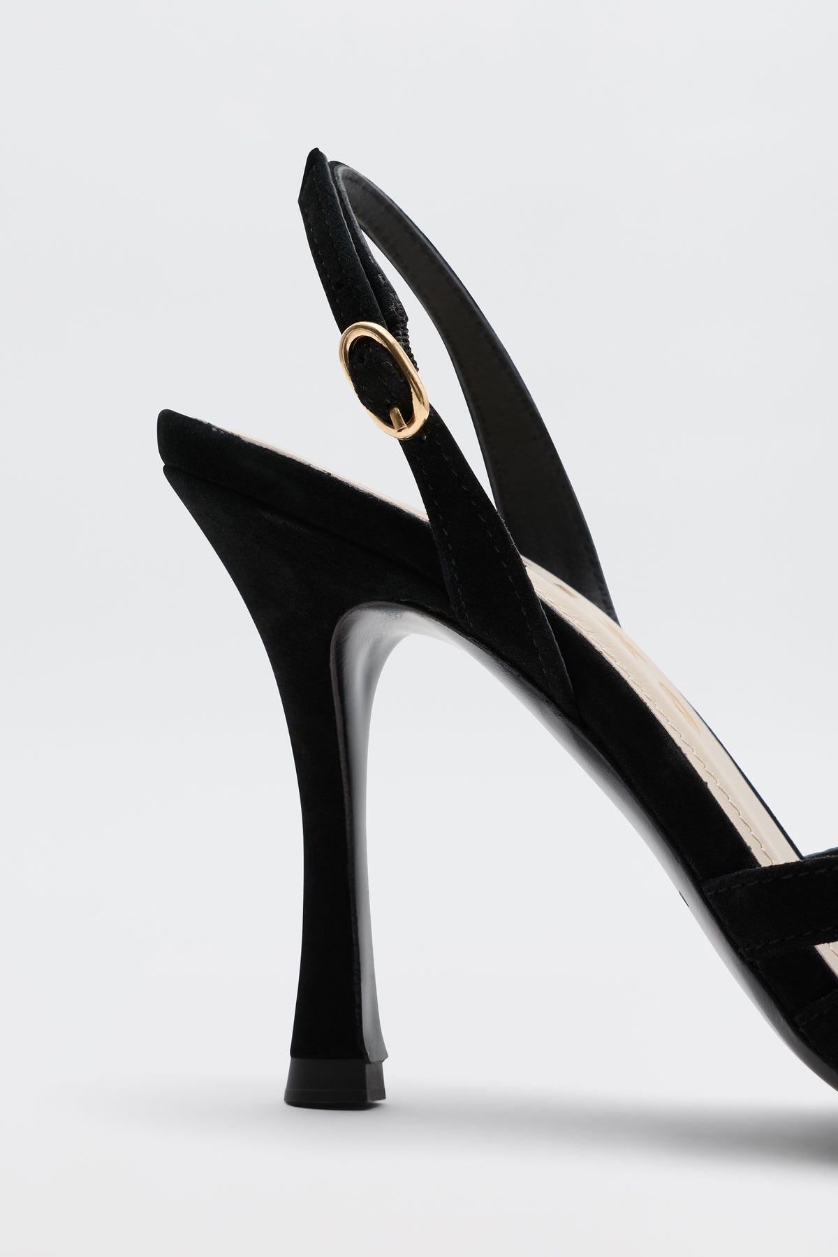 A close-up side view of the Mavi - Black high-heeled sandal featuring a gold buckle on the ankle strap, perfect for elevating any outfit, set against a plain light background.