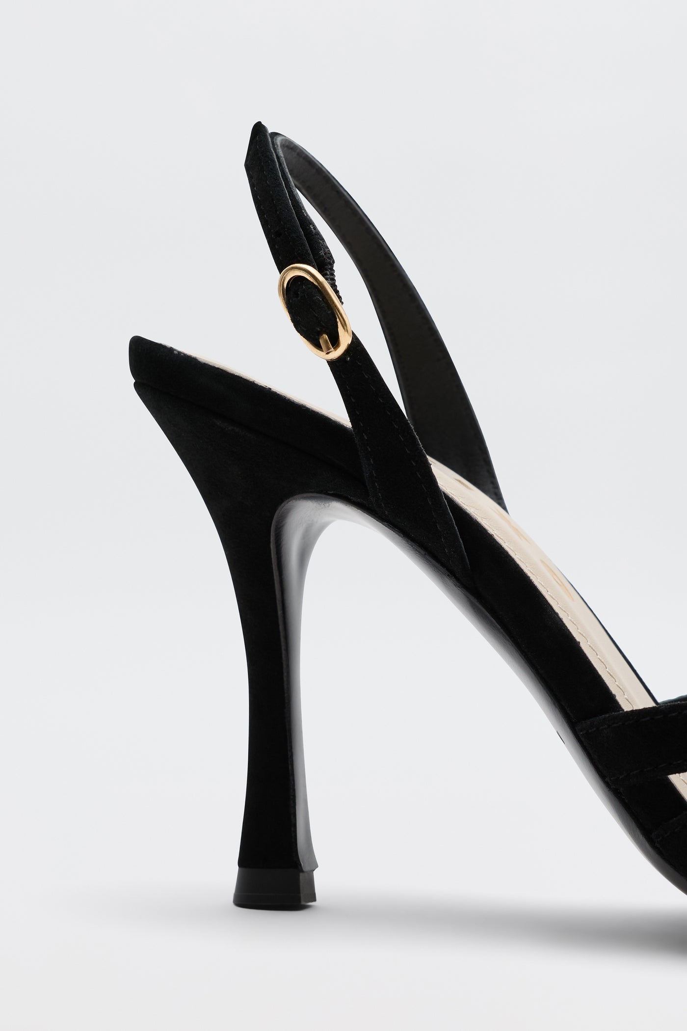 A close-up side view of the Mavi - Black high-heeled sandal featuring a gold buckle on the ankle strap, perfect for elevating any outfit, set against a plain light background.