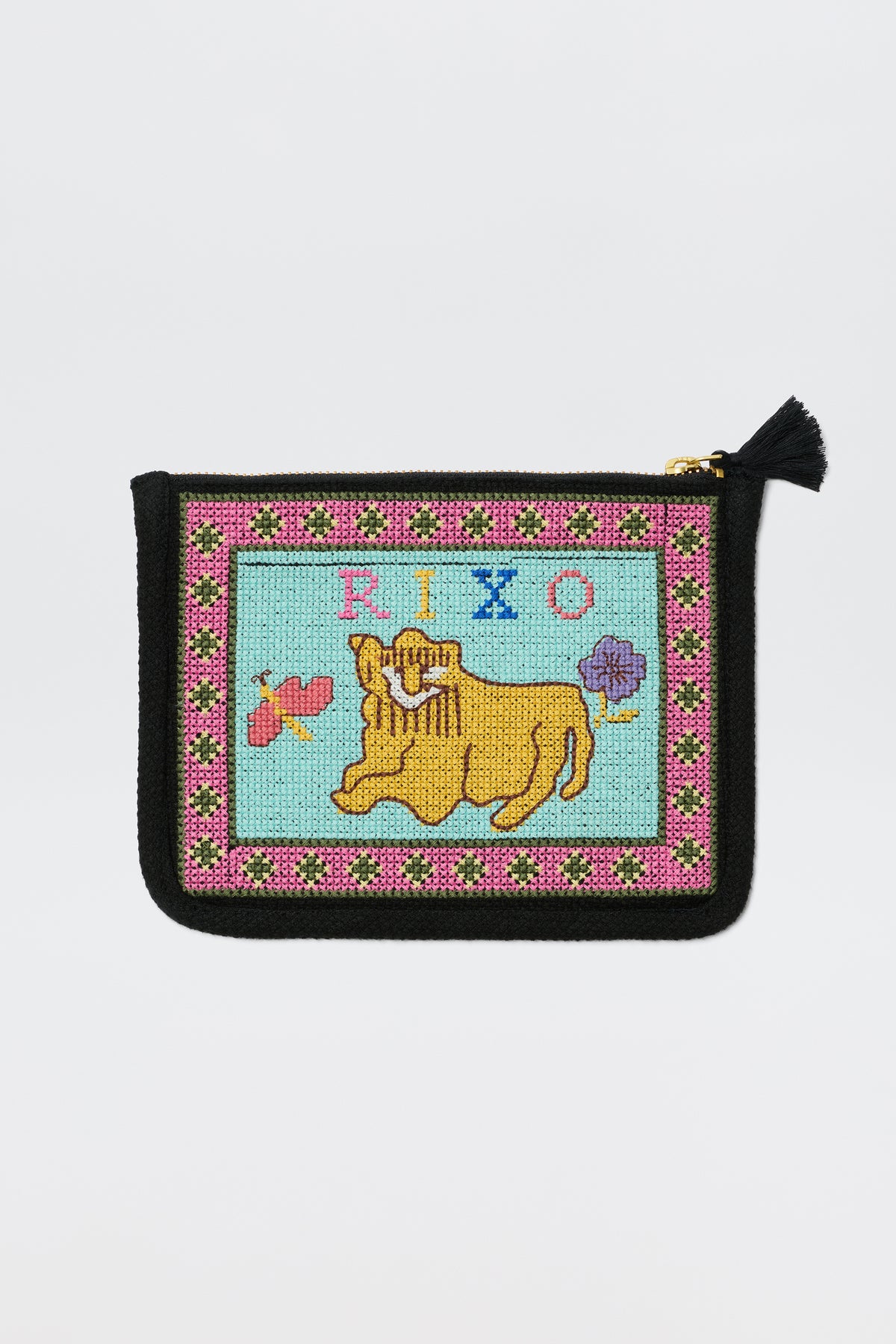A charcoal zippered pouch featuring the Reiko Mini Leo cross stitch embroidery design, with a yellow dog, the word "PIPO," a butterfly, a flower, and a colorful border on a light blue background.