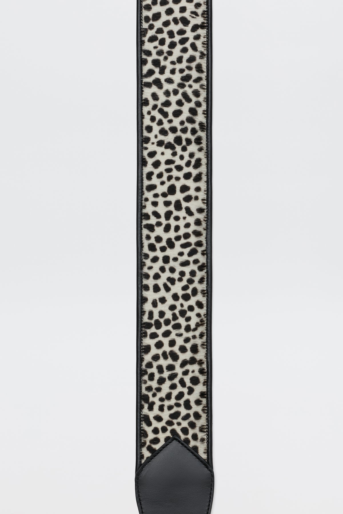 A close-up of the Calista - Zandra Animal Brown guitar strap, featuring a black and white animal print pattern with black leather ends, displayed against a plain white background.