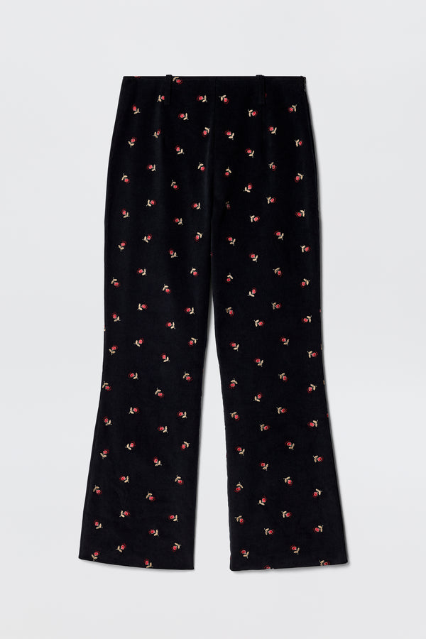 Olwen - Dandy Embroidery Deep Navy fit and flare trousers in black velvet, straight leg, with small red and green embroidered flowers. Vintage-inspired tailoring style shown laid flat on a light gray background.