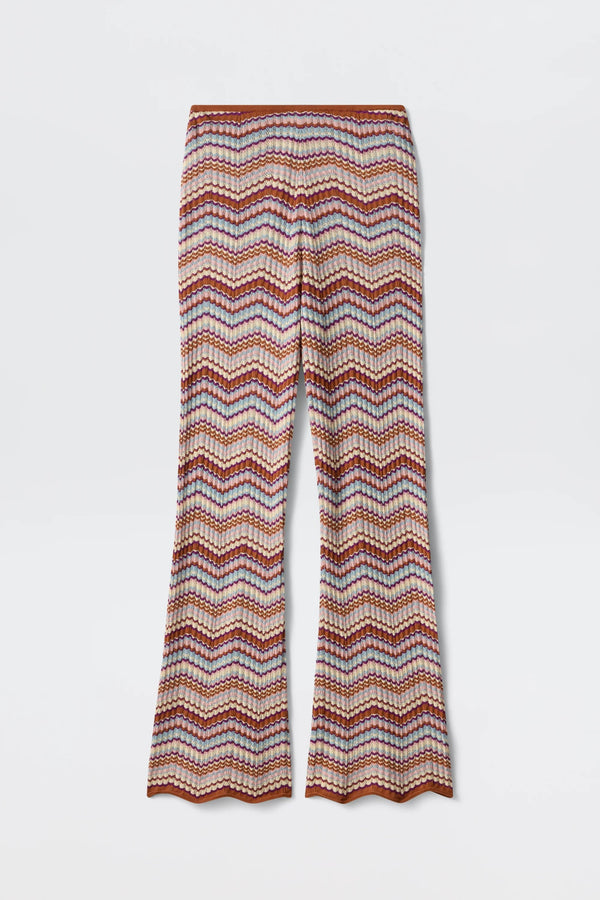 Boni - Maria Chevron Multi pants showcase a vibrant chevron zigzag pattern in orange, pink, and white hues. Crafted from breathable cotton knit, these flared-leg trousers feature a scalloped hem at the bottom, making them a versatile wardrobe essential.