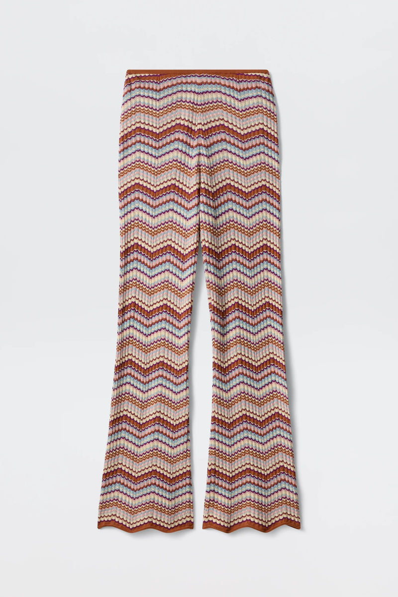 Boni - Maria Chevron Multi pants showcase a vibrant chevron zigzag pattern in orange, pink, and white hues. Crafted from breathable cotton knit, these flared-leg trousers feature a scalloped hem at the bottom, making them a versatile wardrobe essential.