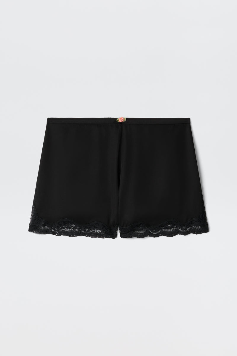 Lealia - Black satin shorts featuring a lace-trimmed hem and a delicate rose detail at the waistband, shown on a plain white background.