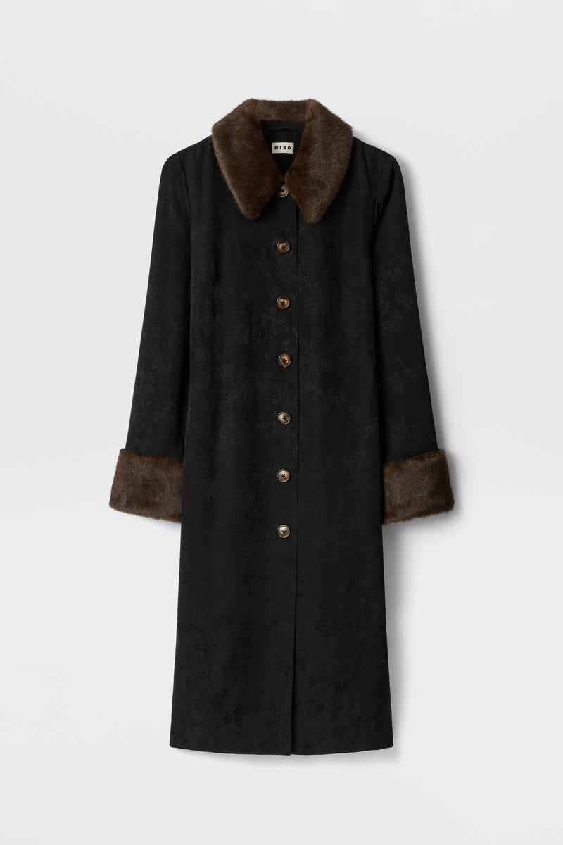 The Jonah - Black coat features a long black design with brown faux fur collar and cuffs, subtle textured pattern, and brown front buttons, shown against a plain white background.