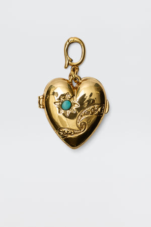 The Veyra - Gold is a gold heart-shaped locket with ornate cosmic-inspired designs, featuring a star pattern set with a blue gemstone and a decorative top clasp, displayed against a plain white background.