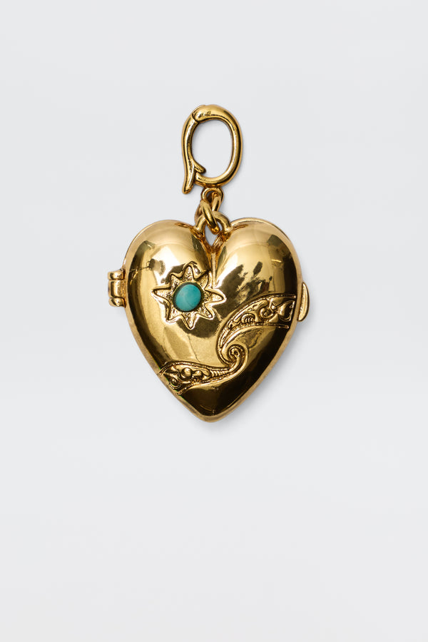 The Veyra - Gold is a gold heart-shaped locket with ornate cosmic-inspired designs, featuring a star pattern set with a blue gemstone and a decorative top clasp, displayed against a plain white background.