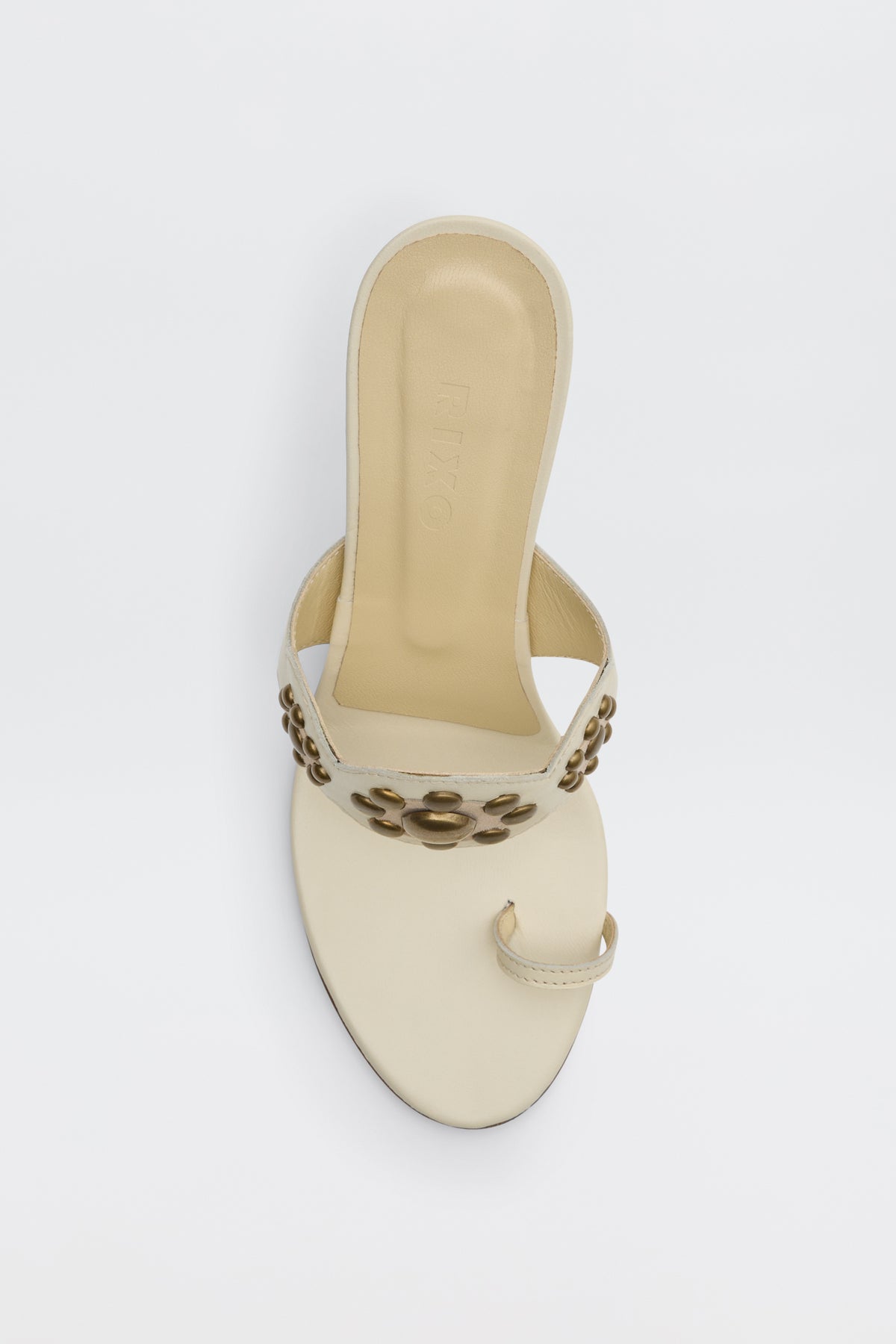 Esmeray - Cream: A cream open-toe sandal featuring a toe ring and a wide strap adorned with gold flower-shaped embellishments, shown from above against a white background.