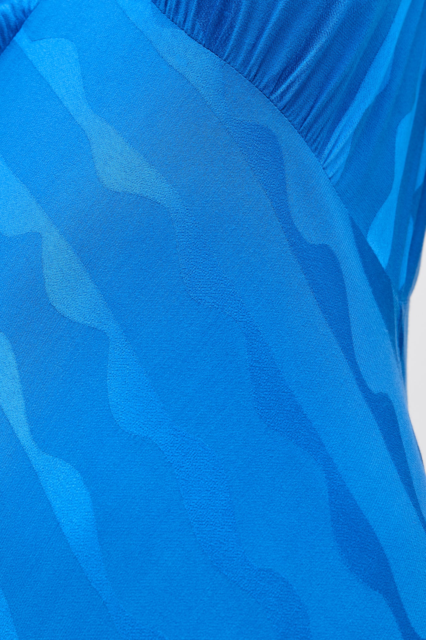 Close-up of the Sandrine - Wave Jacquard Blue, showcasing its wavy, textured blue patterns. The smooth, stretchy fabric is ideal for versatile styling and serves as a perfect transitional staple in any wardrobe.