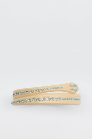 The Shereen - Cream headband features rows of small, round turquoise and clear rhinestones on a beige band, shown against a plain white background.