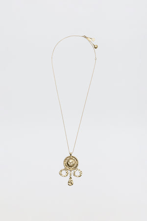 The Zahra - Gold necklace features a circular ornate pendant with intricate designs and three teardrop charms, shown against a plain white background.